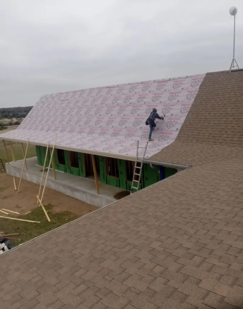 Worker preparing underlayment for a metal roof installation in Madison